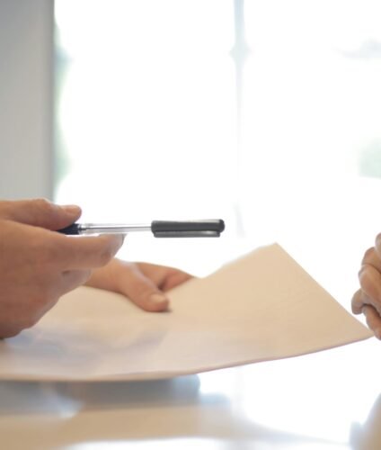 Close-up of a contract signing with hands over documents. Professional business interaction.
